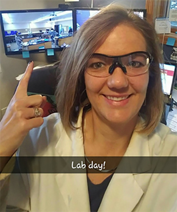 Photo of Beata Ferris in lab coat and lab glasses.
