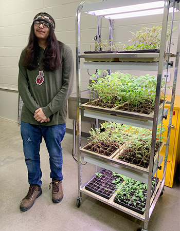 images of stuent standing next to plants.