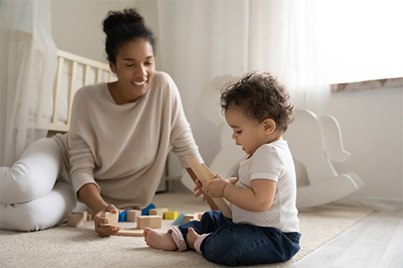 stock photo of child playing block on floor with a parent