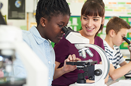 Stock photo of students looking in microscope in science classroom.